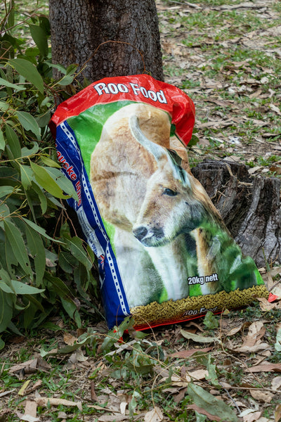 A bag of food sitting on the ground next to a tree