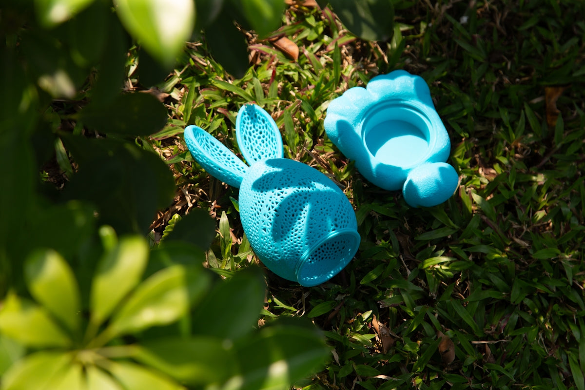Blue easter bunny toy sits on green grass.